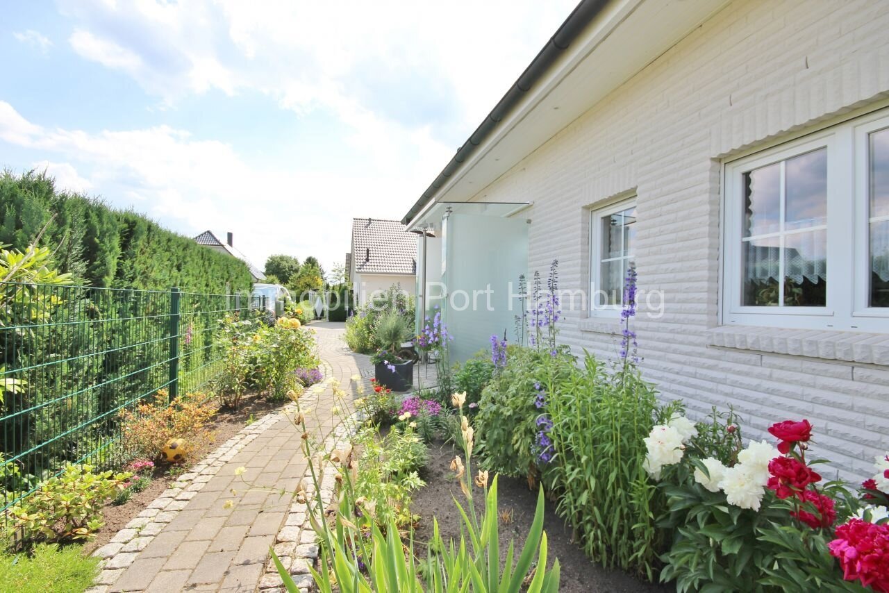 Traumhafte Seiteneinfahrt mit Natursteinpflaster und üppiger Blumenrabatte - Ihr Willkommensbereich mit Charme!